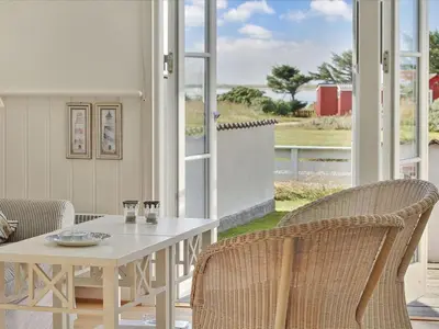 a white table and chairs with a white table and some windows at Apartment Hubertine - 100m to the fjord by Interhome in Vestervig