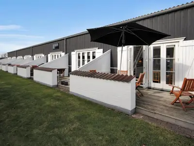 a row of white buildings with a black umbrella at Apartment Benta - 150m to the fjord by Interhome in Vestervig