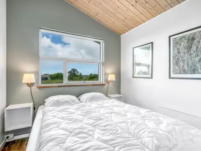 a bedroom with a large white bed with two windows at Holiday Home Selke - 300m to the fjord by Interhome in Vestervig