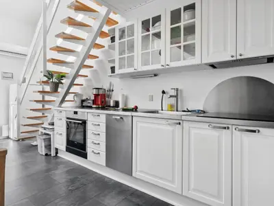 a kitchen with white cabinets and a staircase at Apartment Hermanda - 100m to the fjord by Interhome in Vestervig