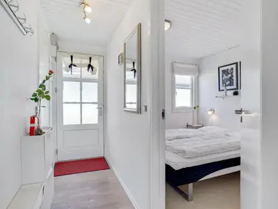 a small white bedroom with a bed and a door at Apartment Idunn - 100m to the fjord by Interhome in Vestervig