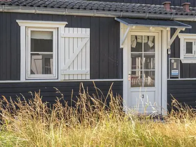 a black house with a white door and windows at Apartment Idunn - 100m to the fjord by Interhome in Vestervig