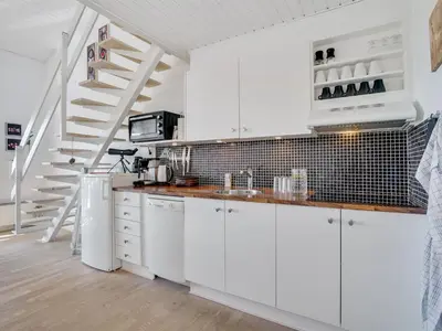 a white kitchen with white cabinets and a staircase at Apartment Idunn - 100m to the fjord by Interhome in Vestervig