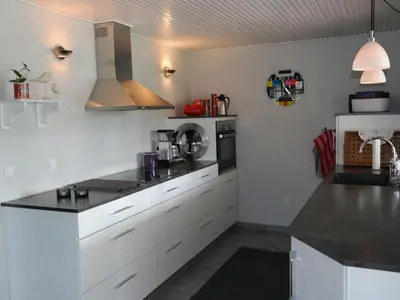 a kitchen with white cabinets and a black counter top at Holiday Home Assarina - 300m to the fjord by Interhome in Vinderup