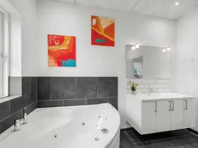 a white bathroom with a tub and a sink at Holiday Home Jarven - 500m to the fjord by Interhome in Højslev