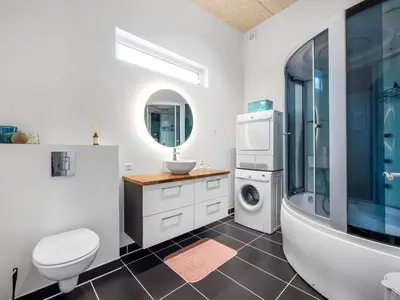 a bathroom with a sink and a toilet and a washing machine at Holiday Home Tenna - 250m to the fjord by Interhome in Højslev