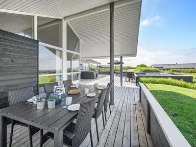 an outdoor deck with a wooden table and chairs at Holiday Home Nahel - 150m to the fjord by Interhome in Vinderup