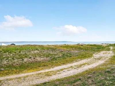a dirt road in a field next to the ocean at Holiday Home Angelita - 80m to the fjord by Interhome in Thyholm