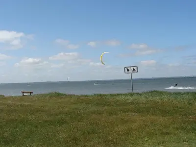a kite is flying over the water at a beach at Holiday Home Brynjolf - 350m to the fjord by Interhome in Vinderup