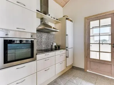 a kitchen with white cabinets and a large tv at Holiday Home Alboldus - 250m to the fjord by Interhome in Vinderup