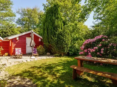 a red cabin with a bench in the yard at Holiday Home Flugha - 500m to the fjord by Interhome in Thyholm