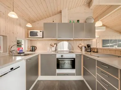 a kitchen with stainless steel appliances and wooden ceilings at Holiday Home Lucio - 350m to the fjord by Interhome in Vinderup