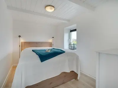 a bedroom with a bed with a blue pillow on it at Holiday Home Ailke - 2km to the fjord by Interhome in Thyholm