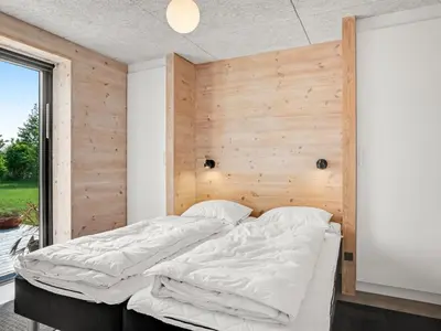 a bed in a room with a wooden wall at Holiday Home Aslag - 150m to the fjord by Interhome in Vinderup