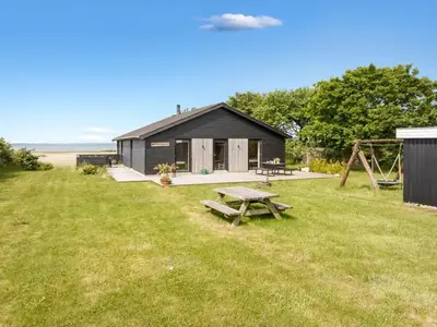 a black cabin with a picnic table in the grass at Holiday Home Aslag - 150m to the fjord by Interhome in Vinderup