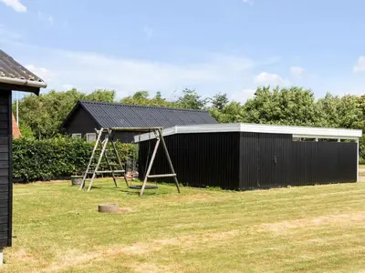 a house with a playground and a black building at Holiday Home Aslag - 150m to the fjord by Interhome in Vinderup