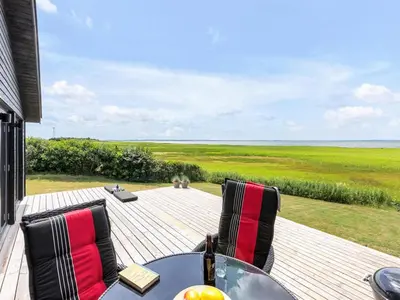 a table and chairs on a deck with a view of the ocean at Holiday Home Aslag - 150m to the fjord by Interhome in Vinderup