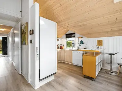a kitchen with white cabinets and a wooden ceiling at Holiday Home Naninja - 300m to the inlet by Interhome in Vinderup