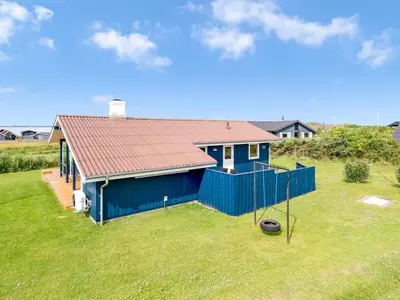 a blue house with a red roof in a yard at Holiday Home Titta - 150m to the fjord by Interhome in Vinderup