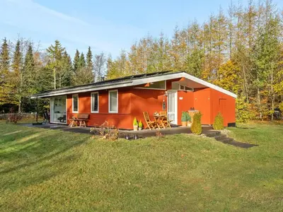 a red cabin in the woods with a yard at Holiday Home Calli - 400m to the fjord by Interhome in Højslev