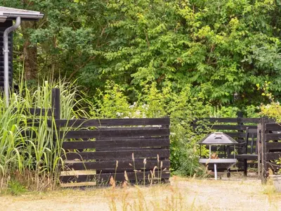 a wooden fence with a bench and a table at Holiday Home Akke - 150m to the fjord by Interhome in Spottrup