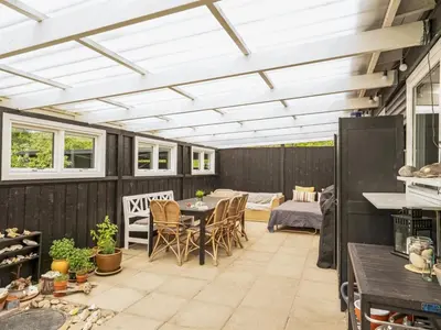 a covered patio with a table and chairs at Holiday Home Akke - 150m to the fjord by Interhome in Spottrup