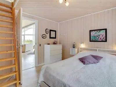 a bedroom with a large bed and a staircase at Holiday Home Regnwald - 400m to the fjord by Interhome in Spottrup