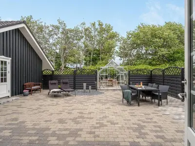a patio with a table and chairs and a greenhouse at Holiday Home Regnwald - 400m to the fjord by Interhome in Spottrup