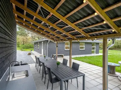 a patio with a table and chairs under a wooden pergola at Holiday Home Veijo - 400m to the fjord by Interhome in Spottrup