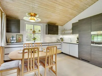 a kitchen with a wooden ceiling and a table and chairs at Holiday Home Blome - 150m to the fjord by Interhome in Højslev