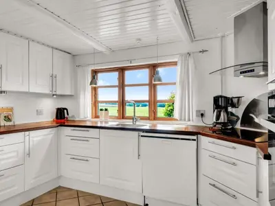 a white kitchen with a sink and a window at Holiday Home Aliza - 300m to the fjord by Interhome in Roslev