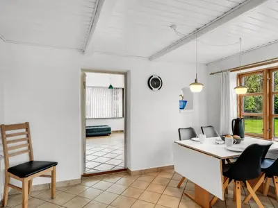 a dining room with a white table and chairs at Holiday Home Aliza - 300m to the fjord by Interhome in Roslev