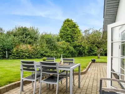 a table and chairs on a patio with a lawn at Holiday Home Aliza - 300m to the fjord by Interhome in Roslev
