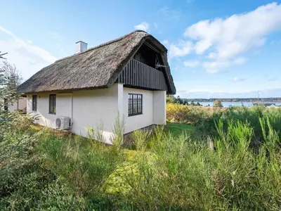 an old house with a thatched roof in a field at Holiday Home Tordis - 250m to the fjord by Interhome in Roslev
