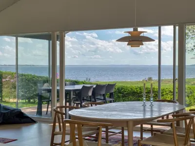 a dining room with a table and chairs and the ocean at Holiday Home Elissa - 50m to the fjord by Interhome in Roslev