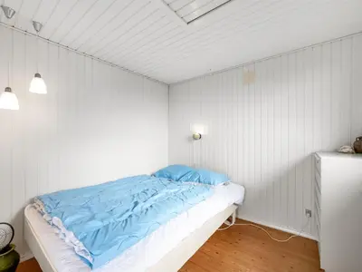 a bedroom with a bed with blue sheets on it at Holiday Home Heera - 100m to the fjord by Interhome in Lihme