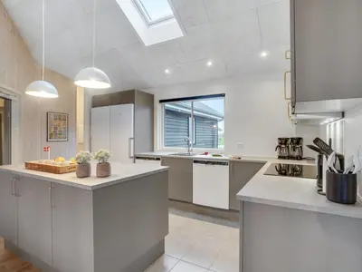 a large kitchen with white appliances and a window at Holiday Home Sibbe - 500m to the fjord by Interhome in Spottrup