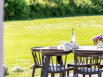 a table with a bottle of wine and two chairs at Holiday Home Kara - 100m to the fjord by Interhome in Fur
