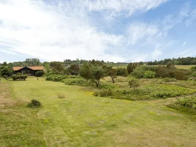 a field of grass with a house in the background at Holiday Home Lok - 90m to the fjord by Interhome in Roslev