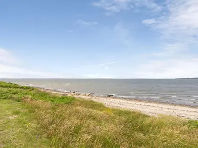 a sandy beach with the ocean in the background at Holiday Home Lok - 90m to the fjord by Interhome in Roslev