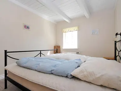 a bedroom with a bed with blue and white sheets at Holiday Home Alois - 1km to the fjord by Interhome in Hesselbjerg