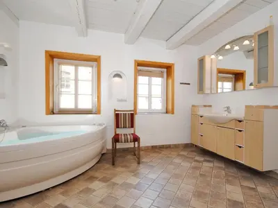 a bathroom with a tub and a sink and a chair at Holiday Home Alois - 1km to the fjord by Interhome in Hesselbjerg