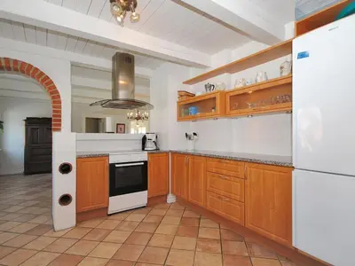 a kitchen with wooden cabinets and a white refrigerator at Holiday Home Alois - 1km to the fjord by Interhome in Hesselbjerg