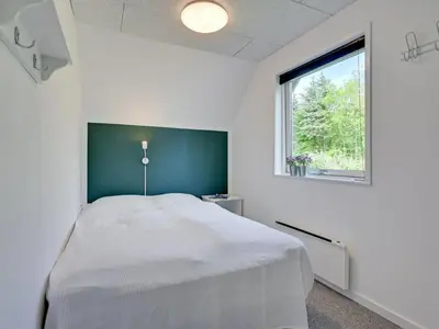 a bedroom with a bed with a green headboard and a window at Holiday Home Femija - 500m to the fjord by Interhome in Roslev