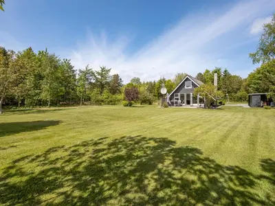 a large grassy yard with a black house at Holiday Home Femija - 500m to the fjord by Interhome in Roslev