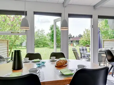 a dining room with a table and chairs and windows at Holiday Home Femija - 500m to the fjord by Interhome in Roslev