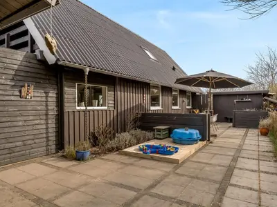 a house with a sandbox and an umbrella on a patio at Holiday Home Thyra - 500m to the fjord by Interhome in Fur