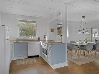 a white kitchen with a table and a dining room at Holiday Home Thyra - 500m to the fjord by Interhome in Fur