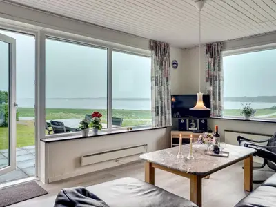 a living room with a table and large windows at Holiday Home Ephra - 250m to the fjord by Interhome in Roslev