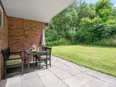 a patio with a table and chairs and a lawn at Holiday Home Ephra - 250m to the fjord by Interhome in Roslev